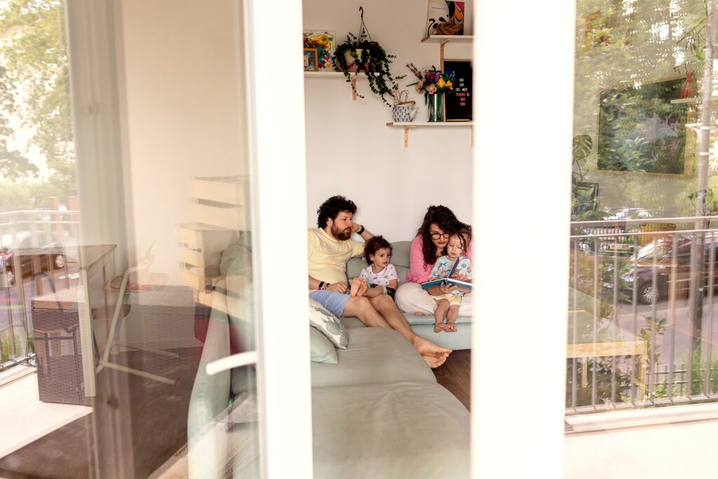 in home photo session, a family sits on the couch reading a book