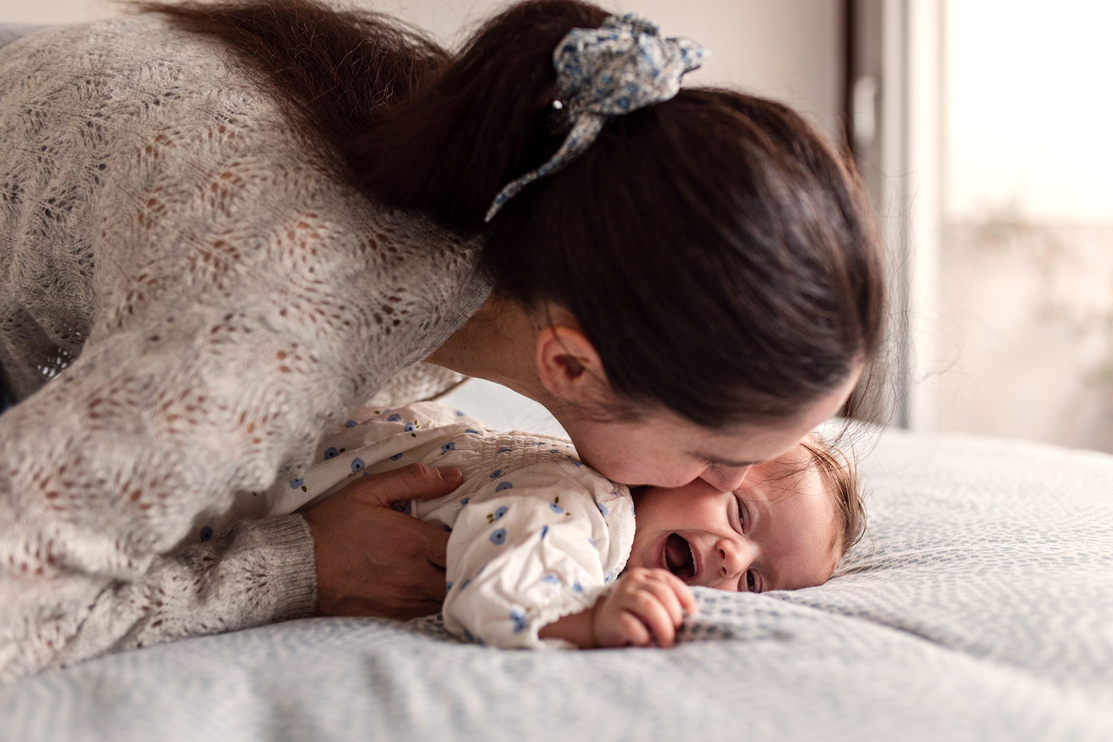 a mother playing with her baby at home, the baby is laughing