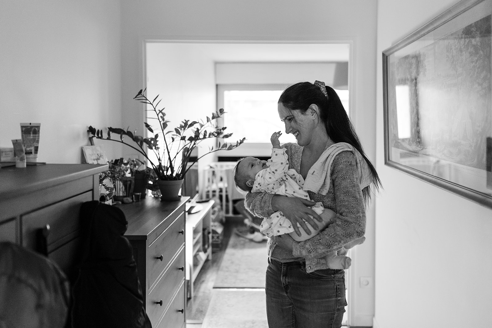 a mother holds her baby in her home, she smiles at her