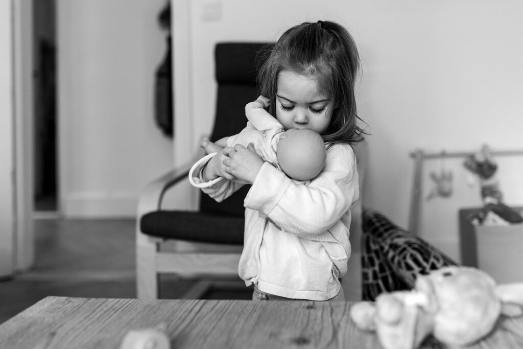 toddler girl kissing her baby doll