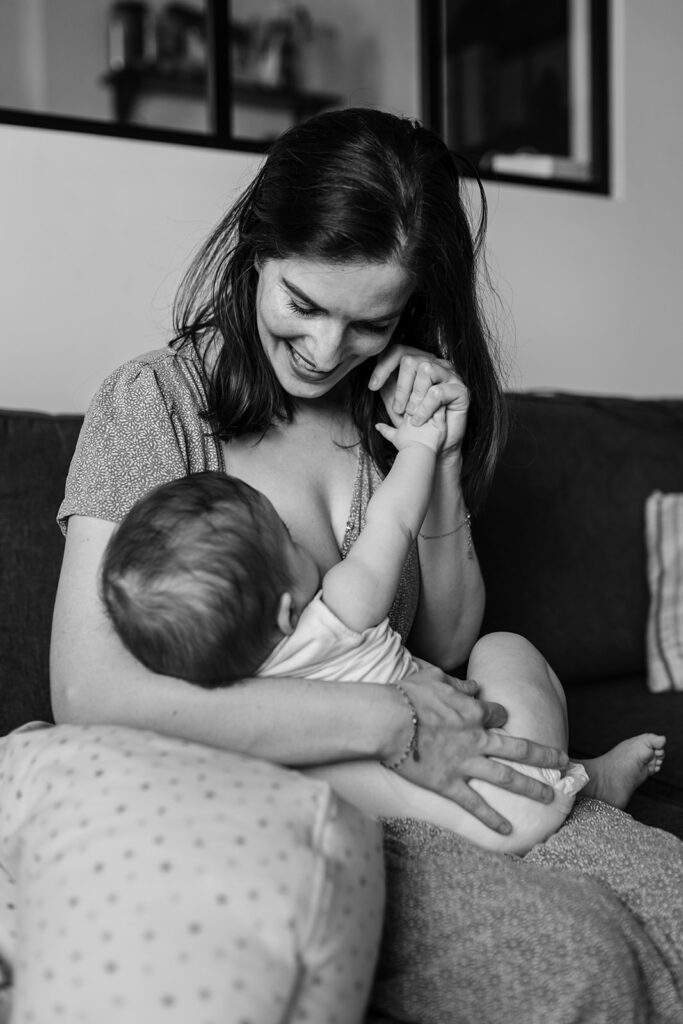 Mother smiling and holding her baby on the sofa at home