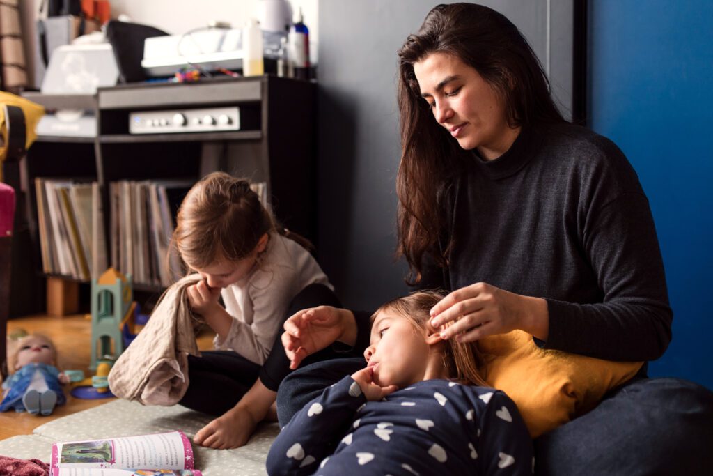 In home photo session : a mother is sitting with her kids on the living room rug to enjoy a cuddle