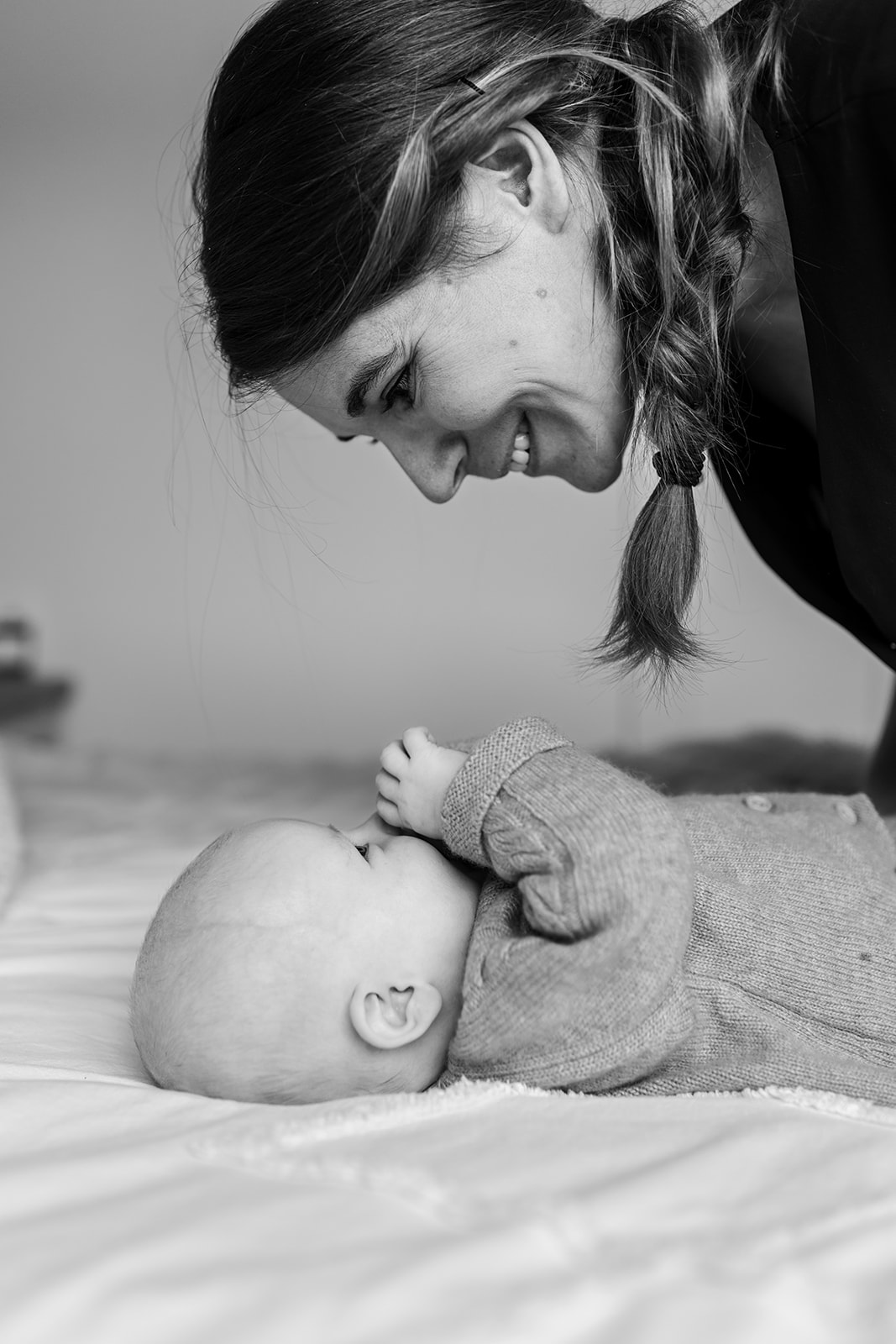 a mother is gazing down at her baby, smiling during a home session with a family photographer Dublin