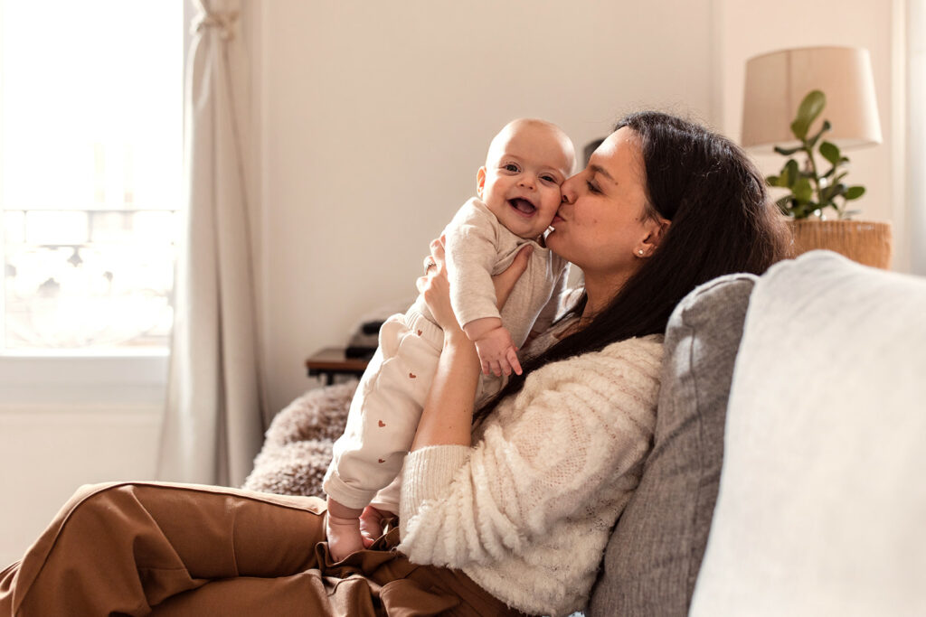 mom kissing smiling baby on the cheek