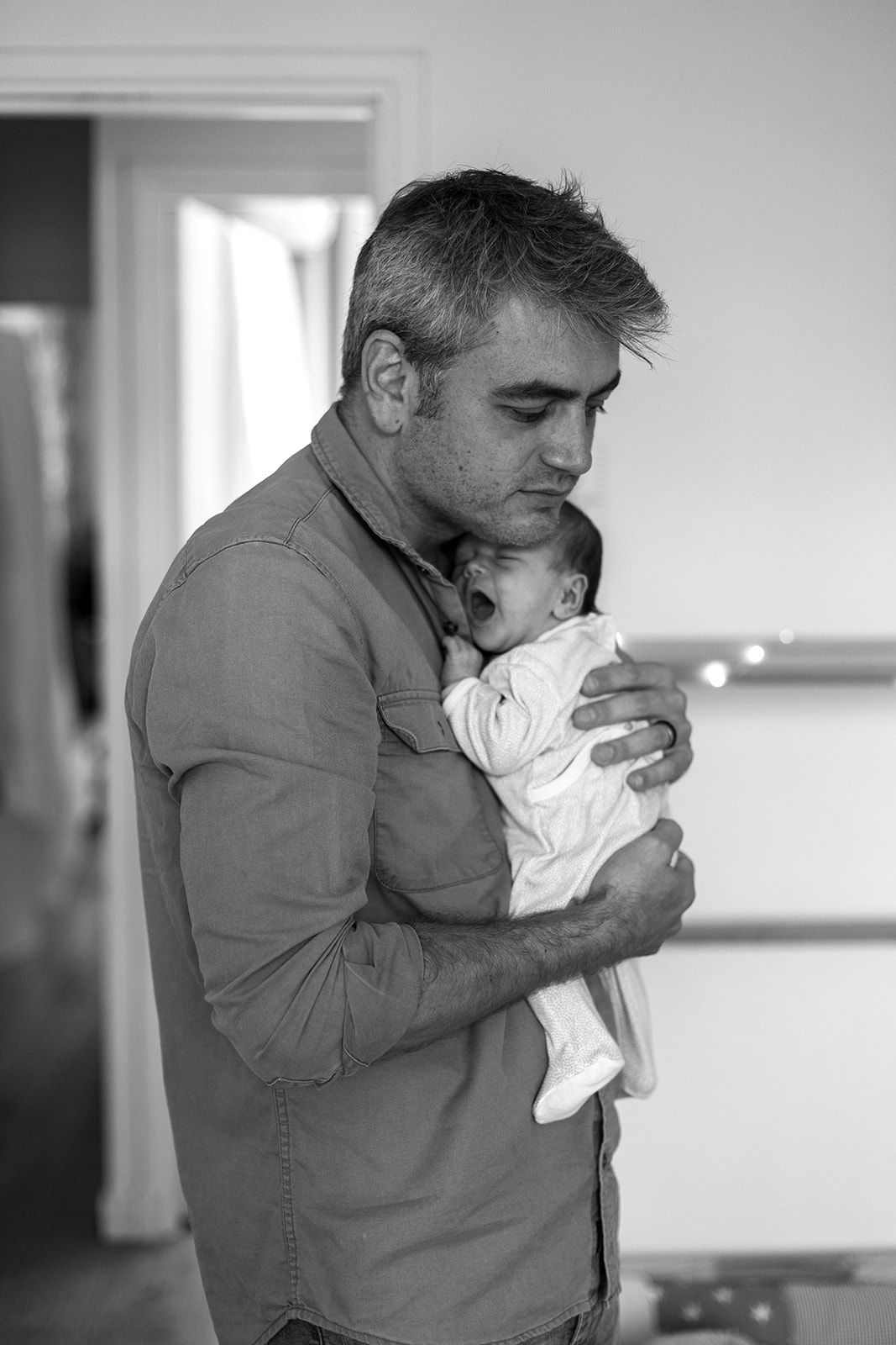 father holding his yawning newborn