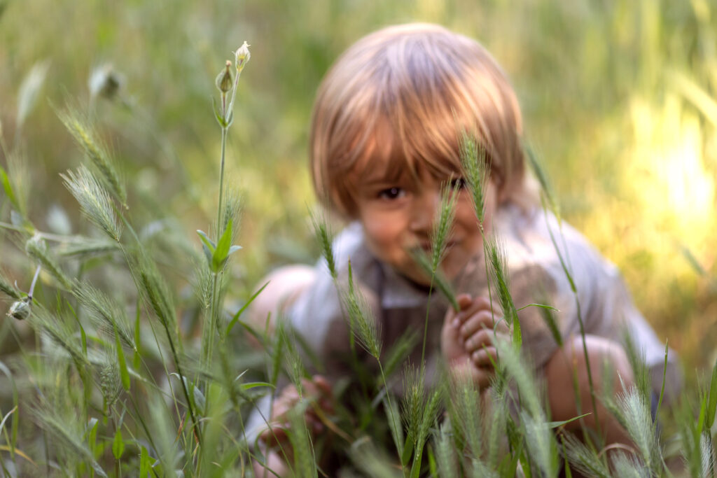 child hiding behind flowers at the park. Tips to get your child ready for a photo session