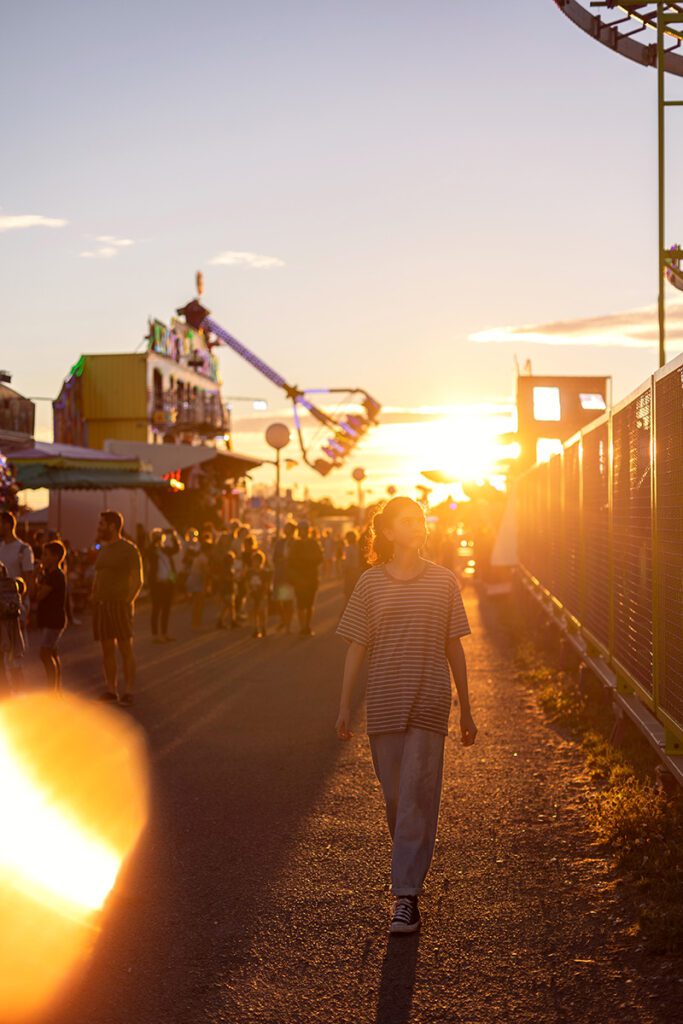 Child walking through an outdoor fair at golden hour
