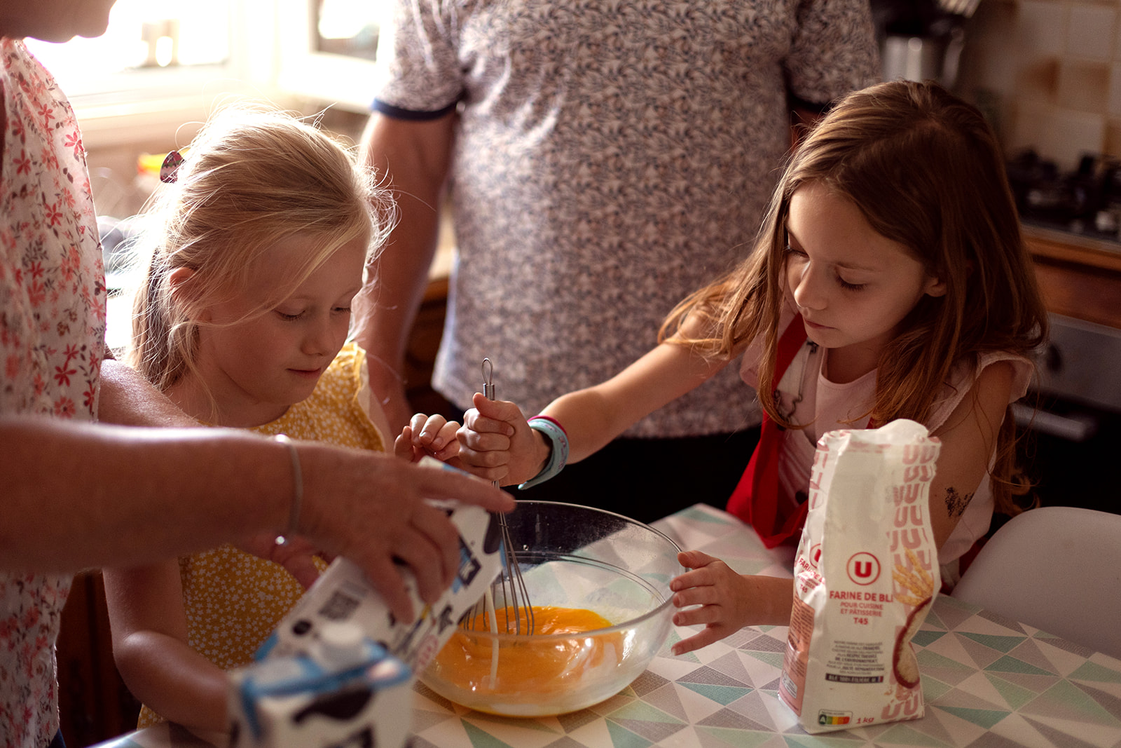 Girl making crêpes with her sister and family in the kitchen