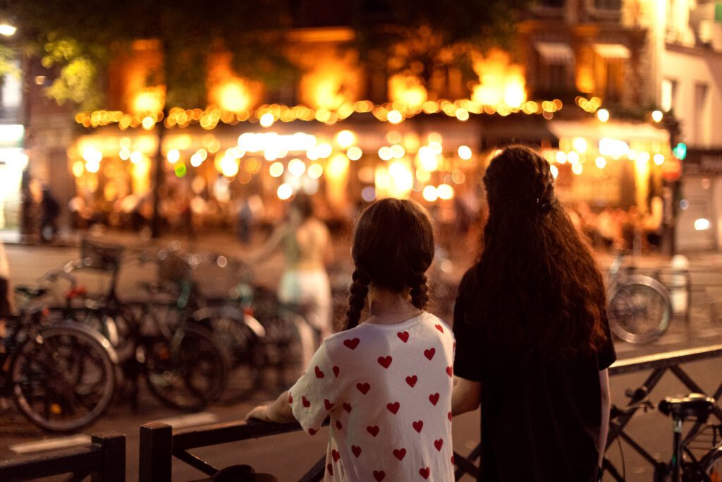 Two children looking over a lively city street at night