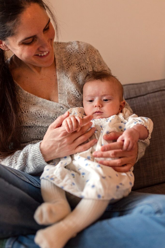 a mother holding her baby in her home and smiling down at her