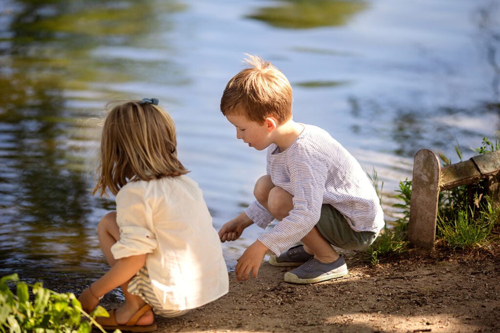 2 kids playing near a lake in a park