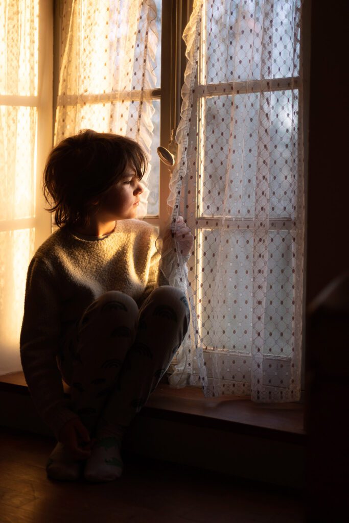 Child sitting by a window in warm morning light