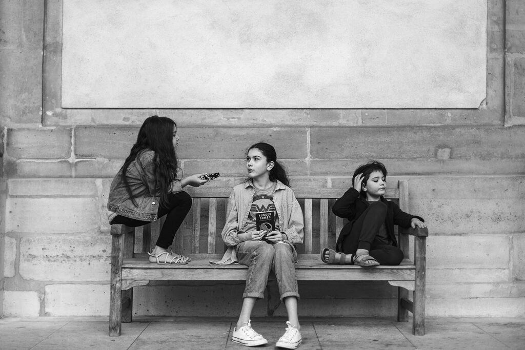 Three children sitting on a bench in a black-and-white travel photograph