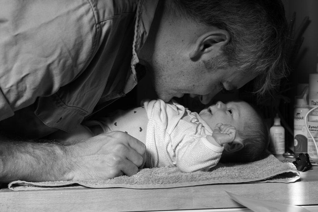 Father leaning close to his newborn baby during a changing moment at home