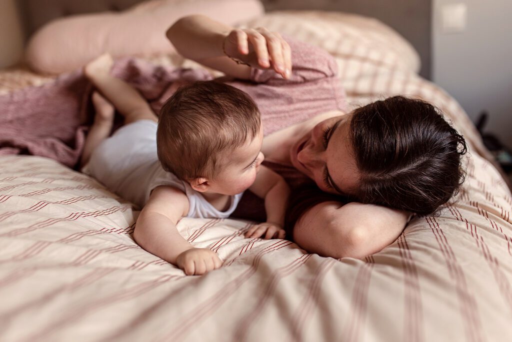 a mother and her baby playing on the bed