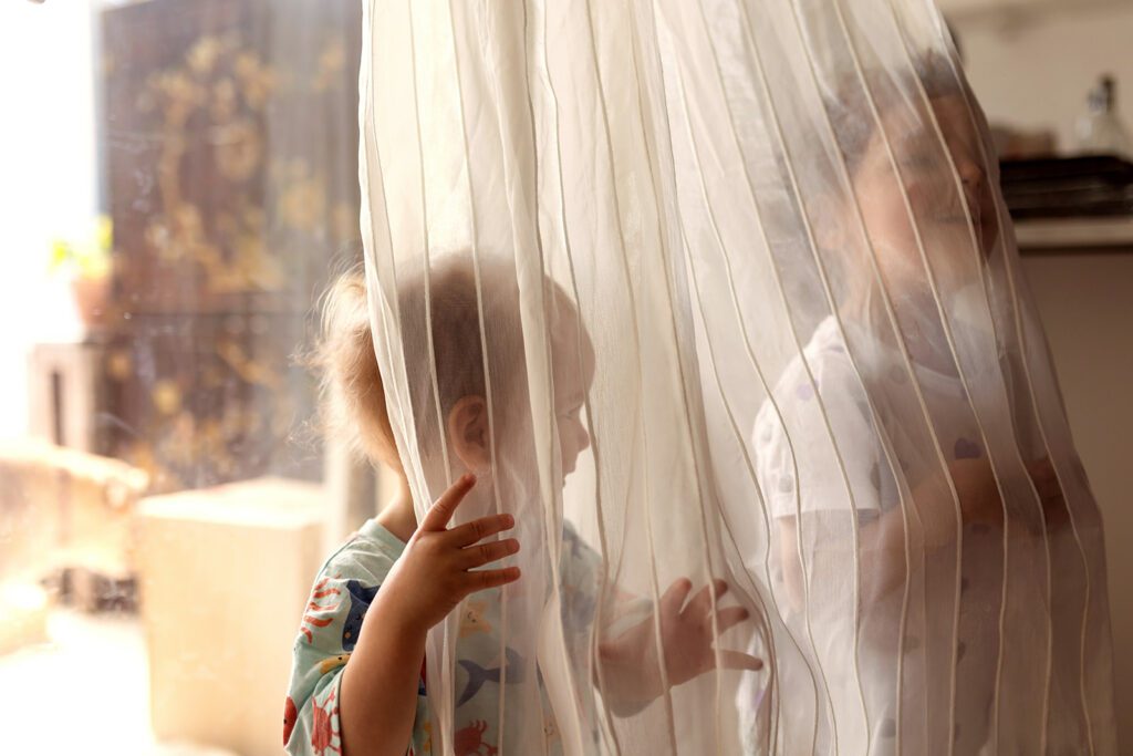 kids hiding behind a curtain to play