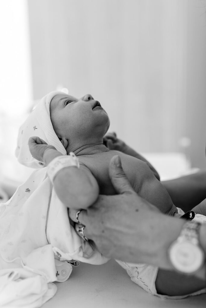 the hands of a mother holding her tiny newborn and dressing her