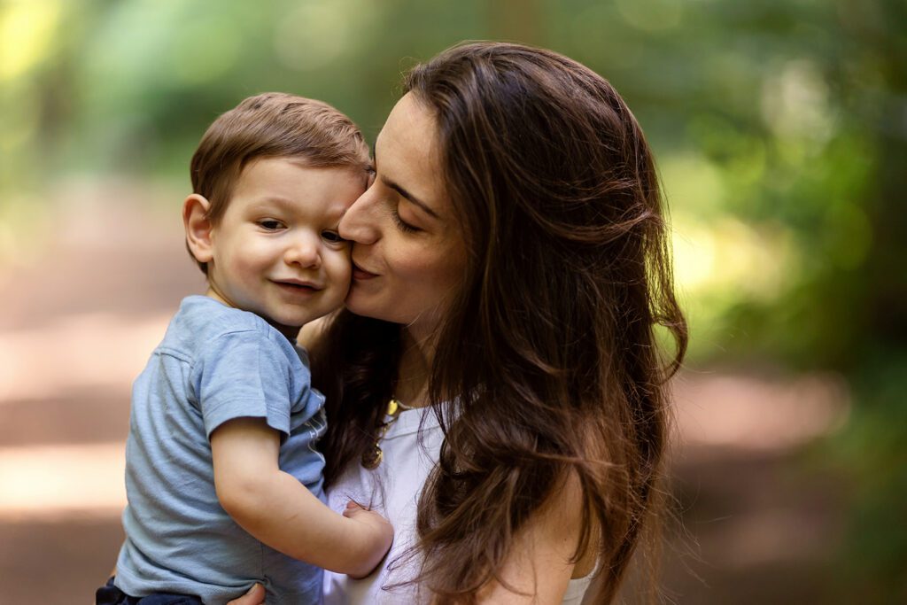 a mother kisses her little boy on the cheek