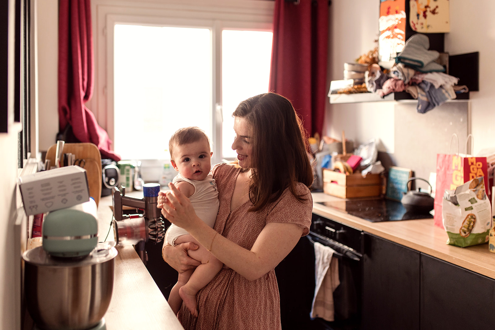 a mother holds her baby in her kitchen