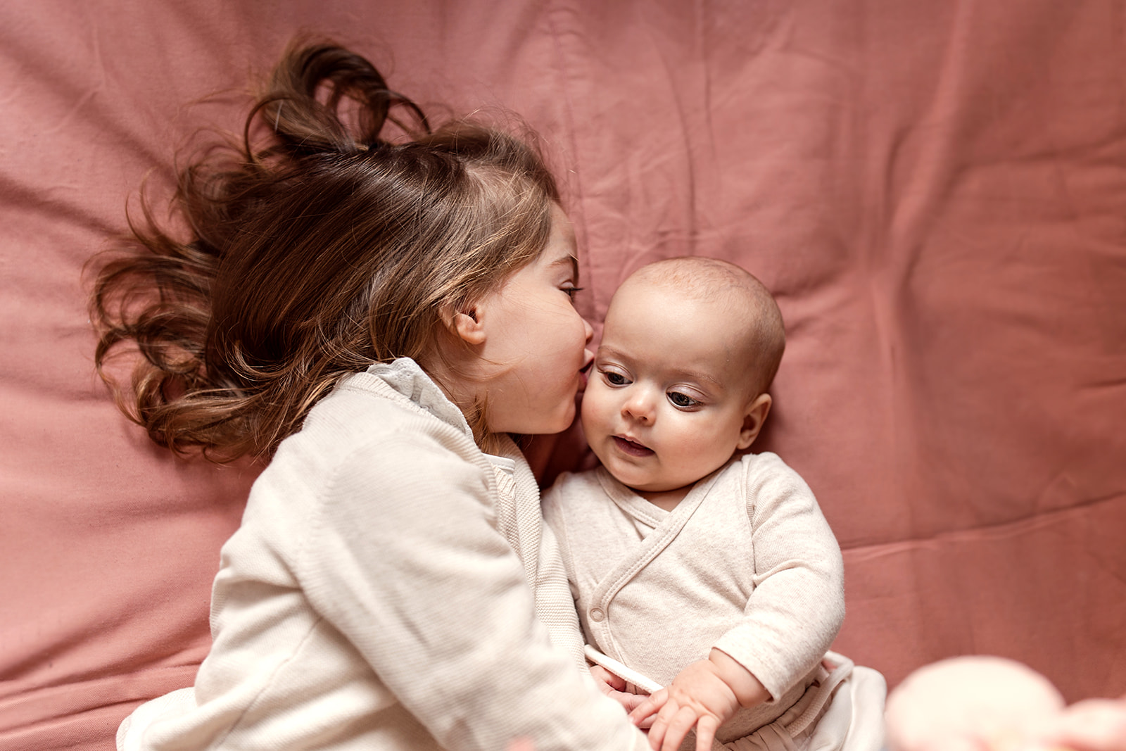 a big sister giving her baby girl a kiss