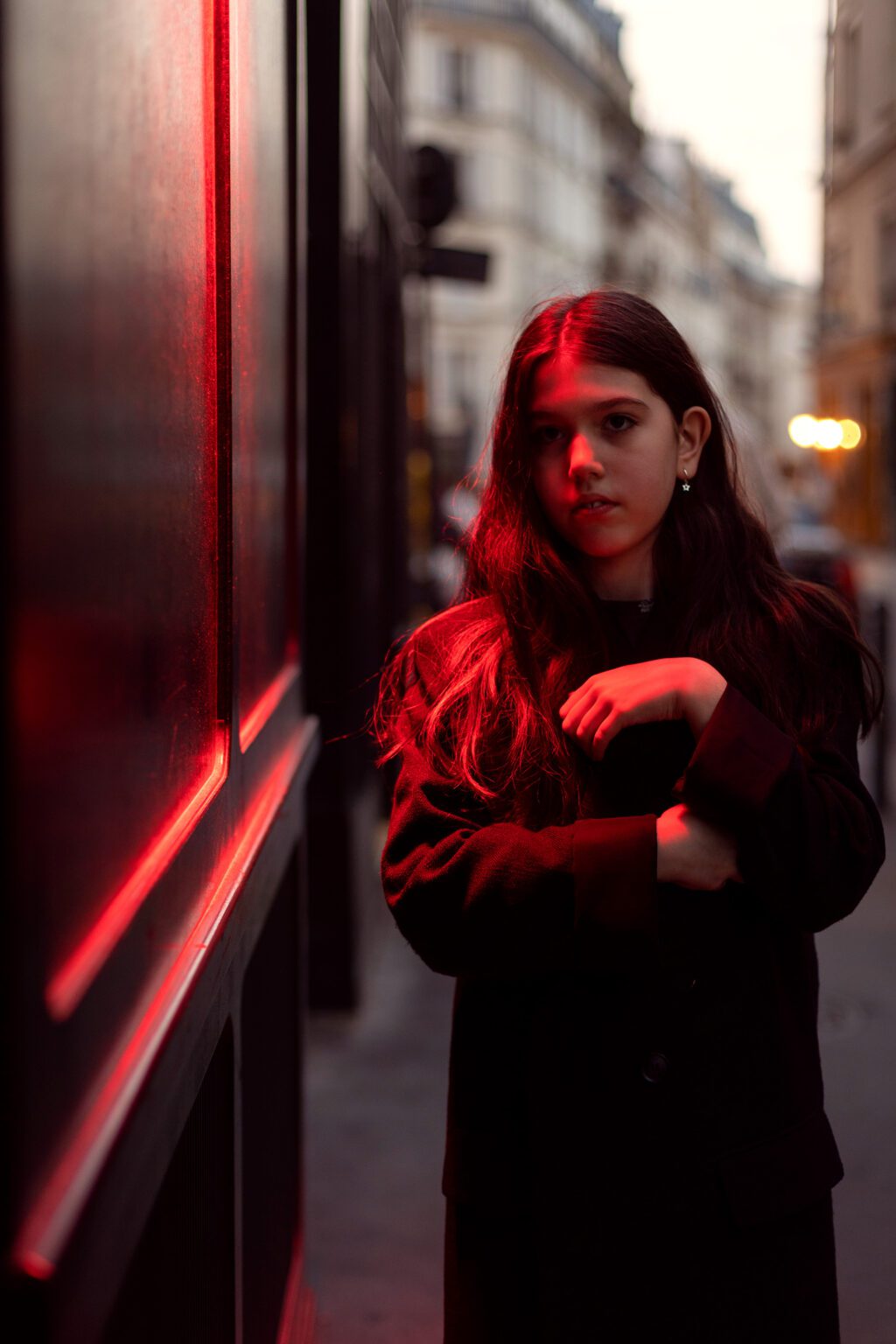 Young girl standing on a city street in red evening light