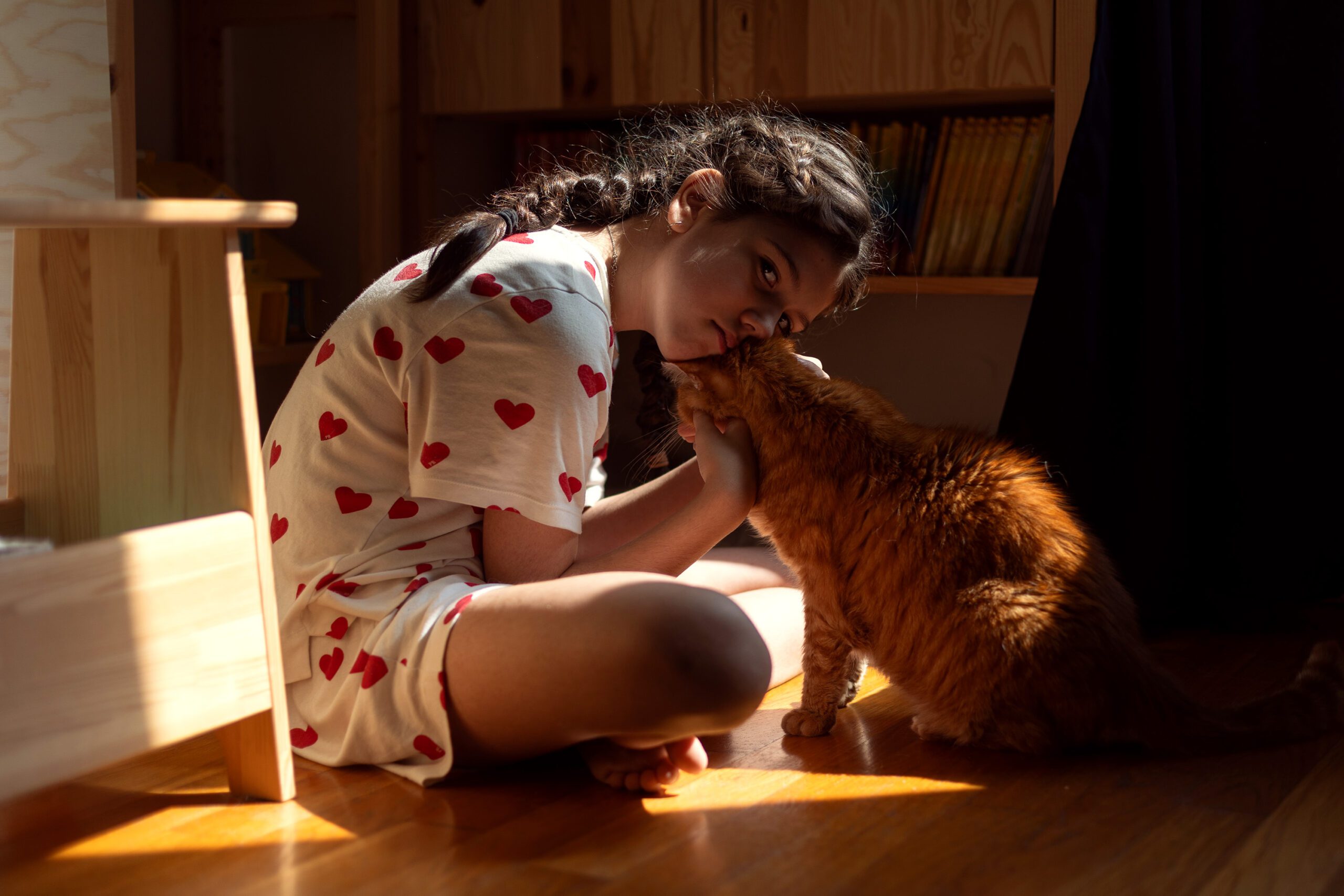 Girl cuddling her cat in warm sunlight at home