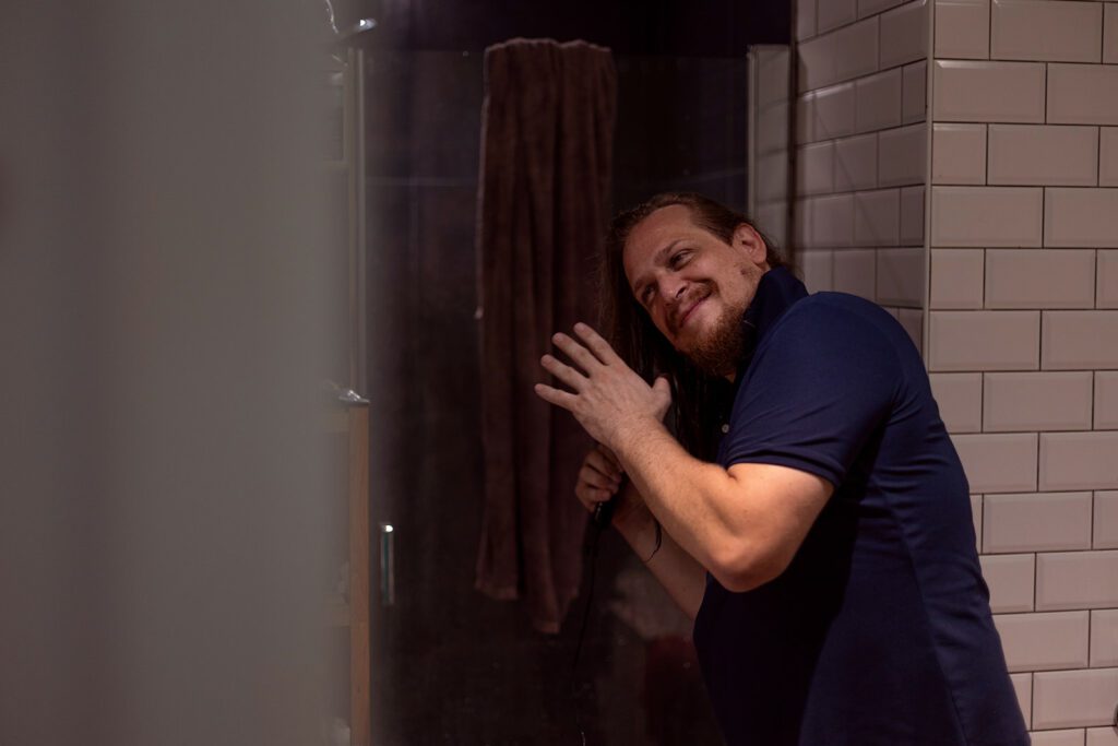 Father brushing his long hair in the bathroom at home