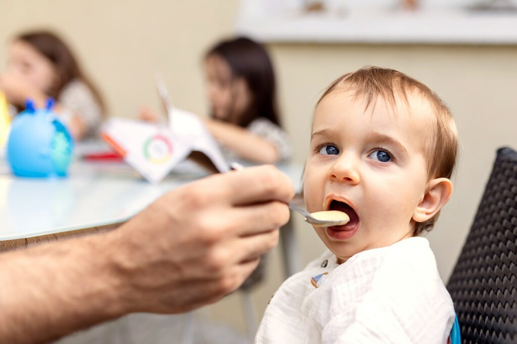 hand of a father spoon feeding his toddler