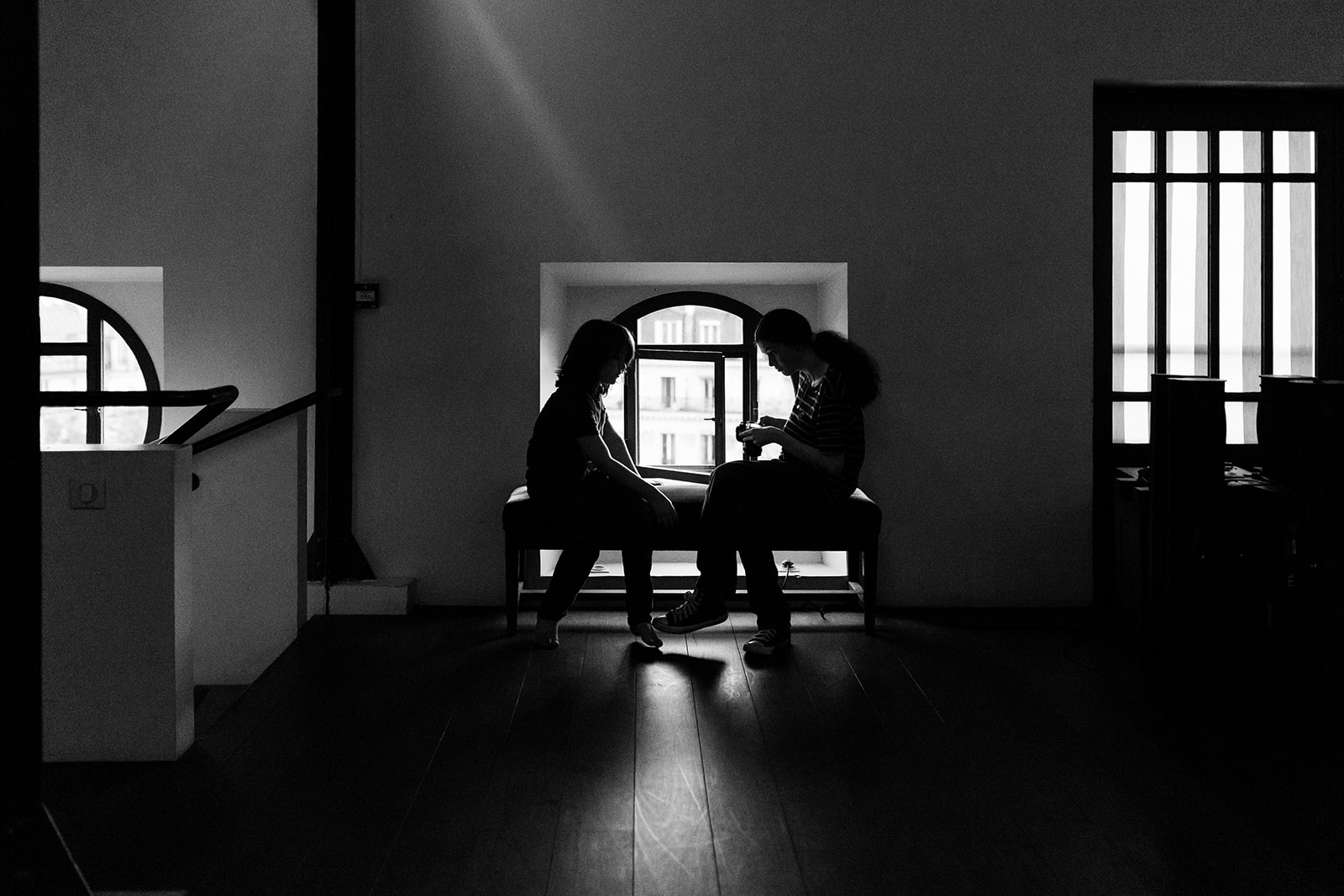 Two children standing beside a round window