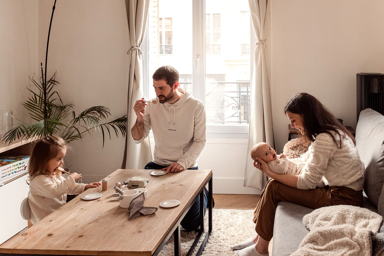 Family playing with a toy tea set together at home