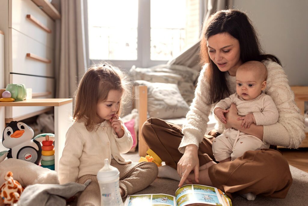 Mother reading a book to her children at home