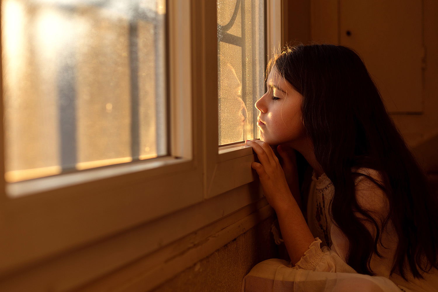 little girl enjoying the sunshine through the window