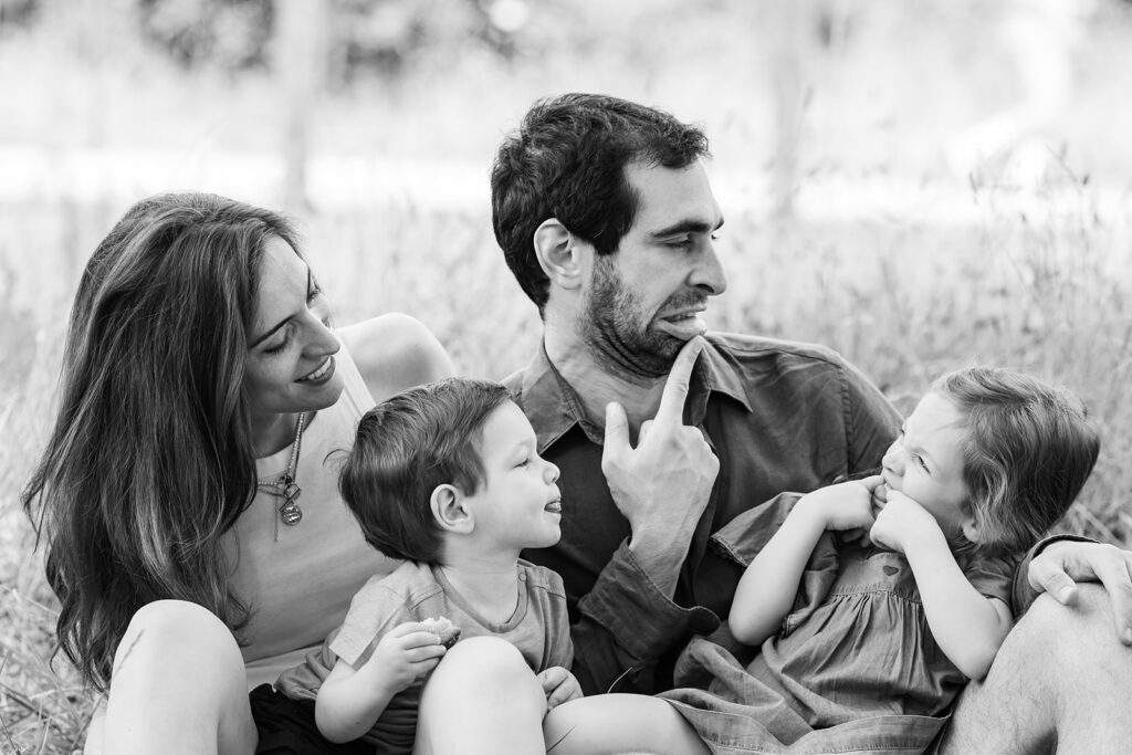 a family is sitting at the park, making silly faces