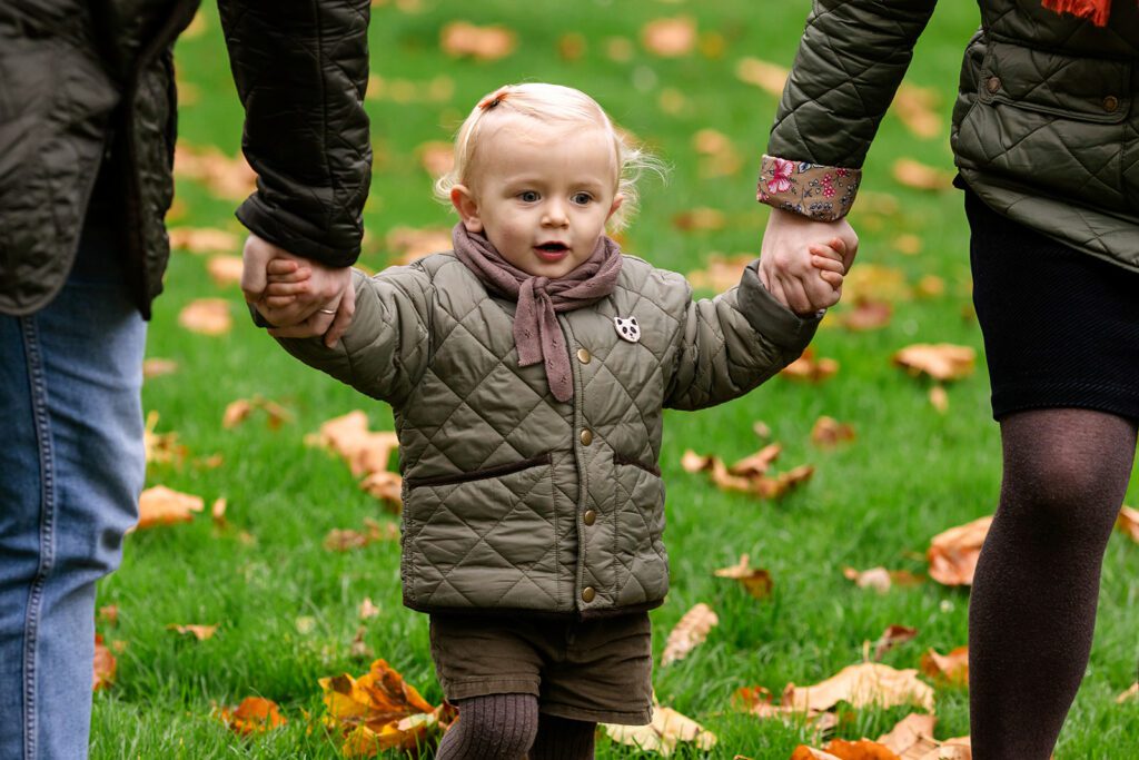 toddler holding the hands of her parents