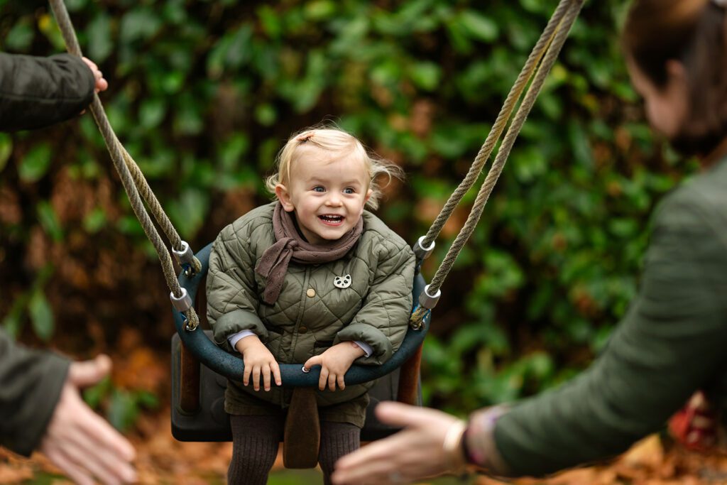 toddler on the swing at the park, smiling