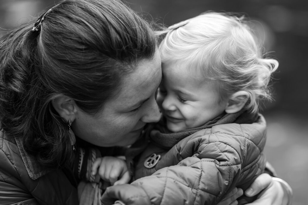 a mother holding and kissing her toddler girl