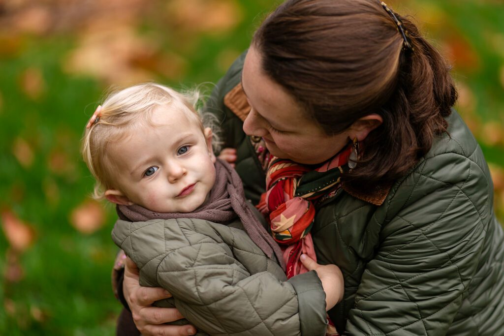 mother holding her toddler at the park in autumn