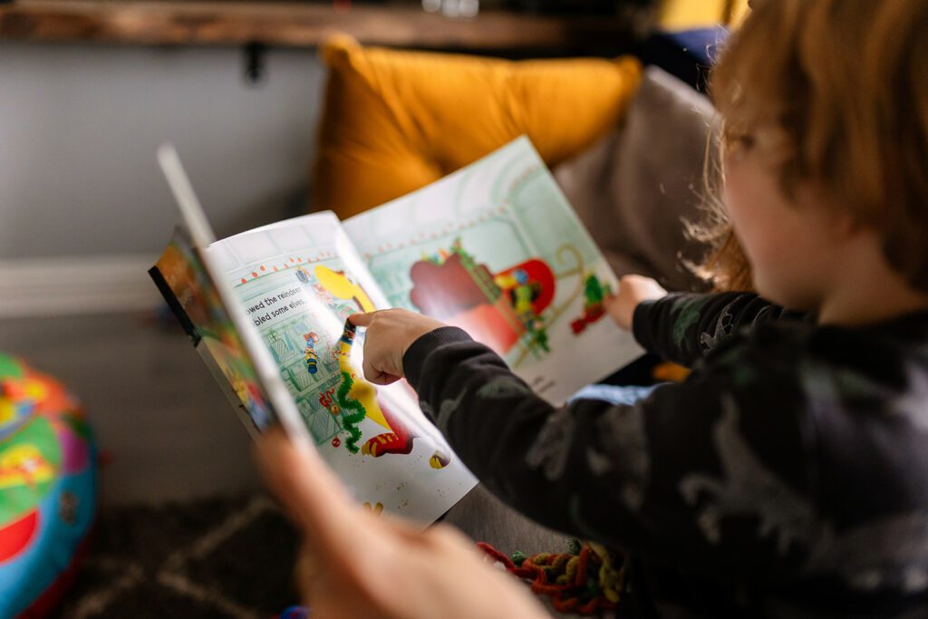 a child reading a book on his mother's lap