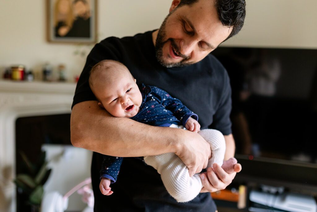 father holding his newborn baby, smiling