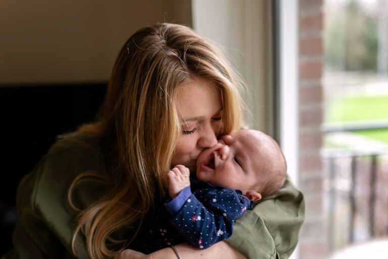 mother kissing her newborn baby