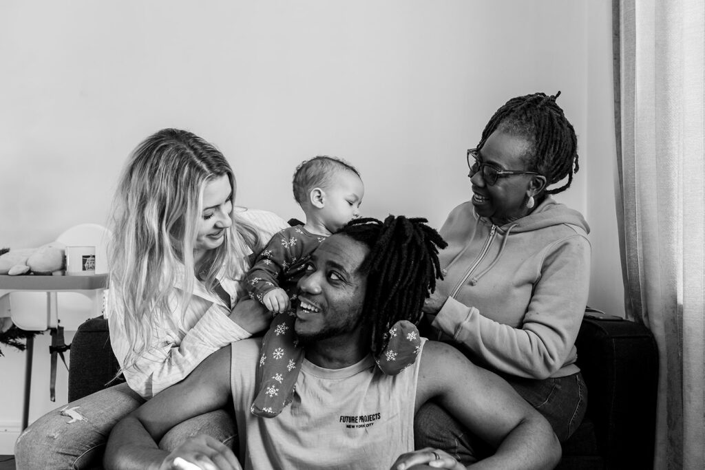 family with parents, grandma and baby smiling at each other