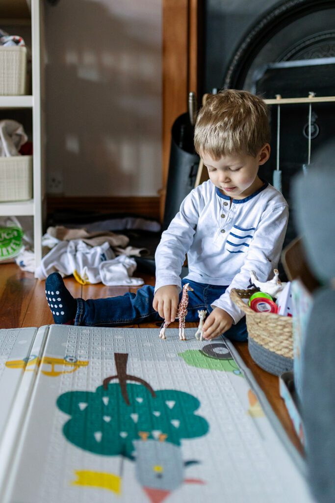 toddler playing with toys during a In home twin baby photos with sibling