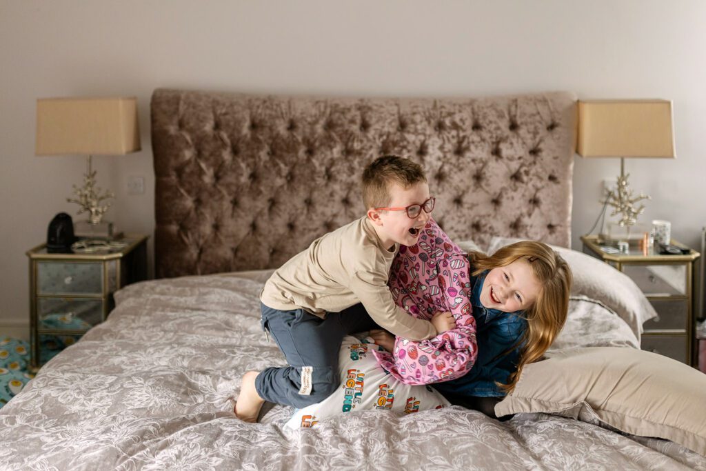 kids jumping and pillow fighting on the bed