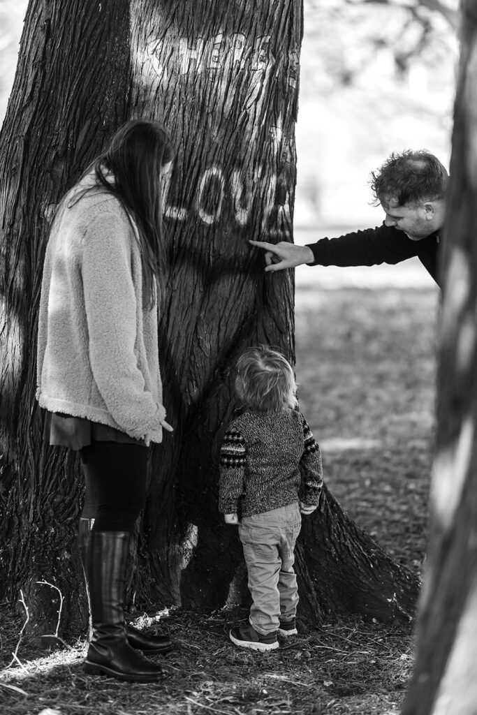 family with toddler looking at a "love" tag on a tree in war memorial garden, dublin