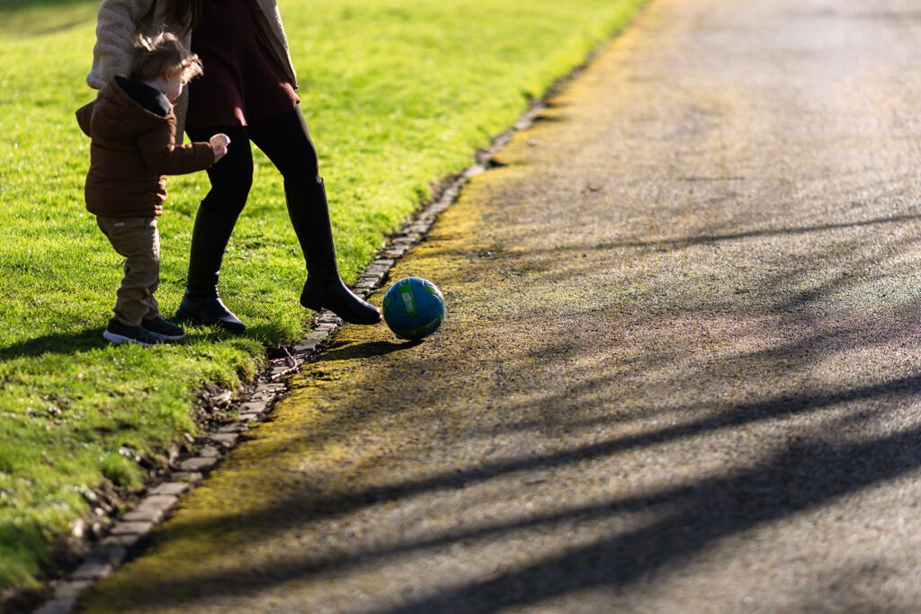 mother and toddler playing football in the park