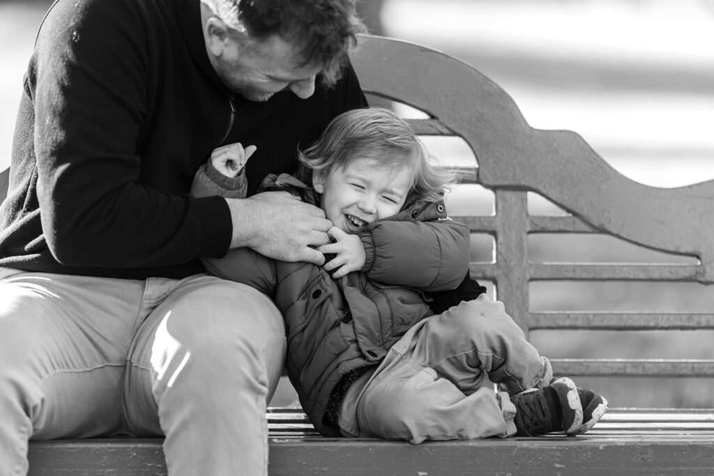 father tickling son and laughing