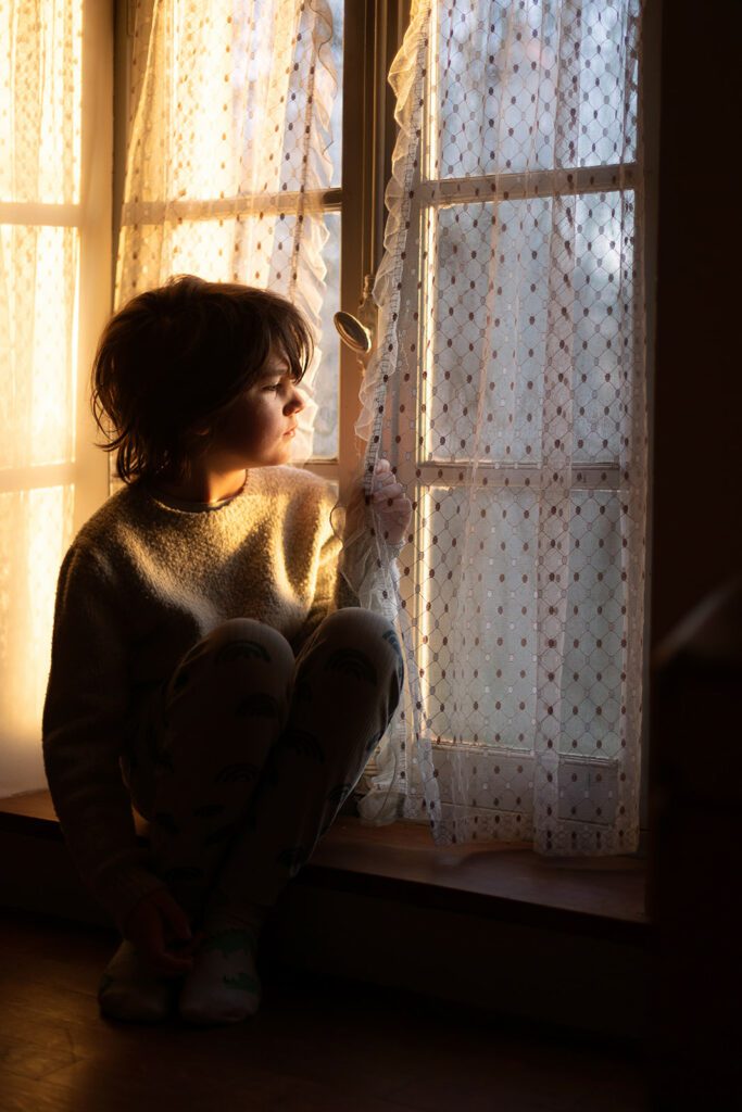 little boy looking out the window at sunrise