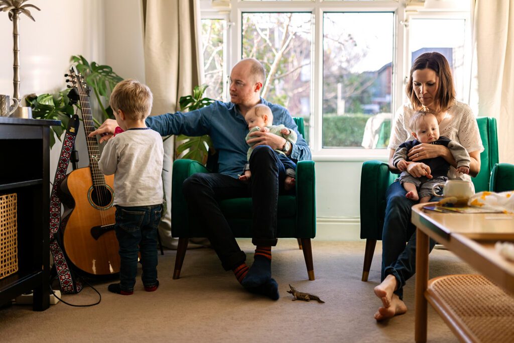 Parents sitting with their young children in the living room at home