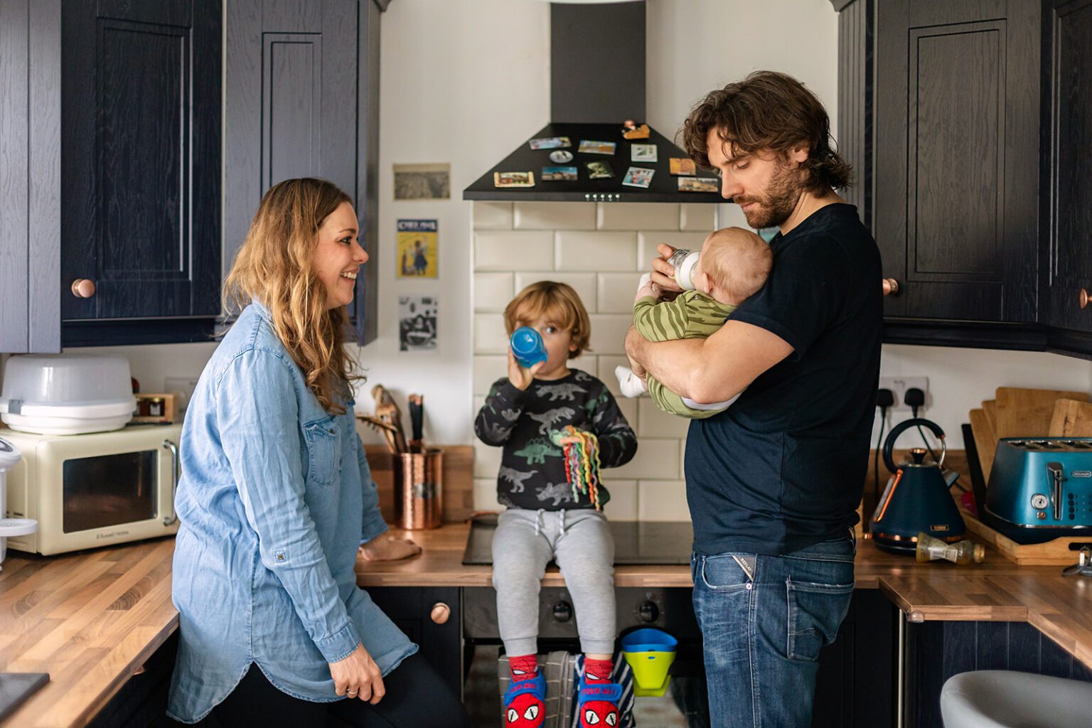 Family together in the kitchen while the father bottle-feeds the baby