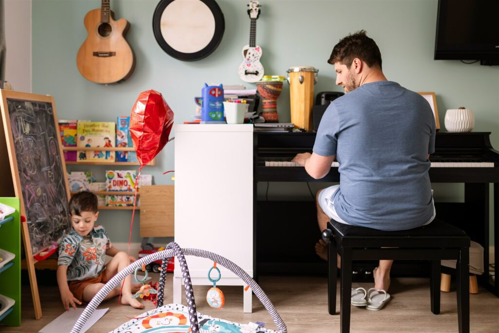 a family home at a photo session, father playing the piano for his son